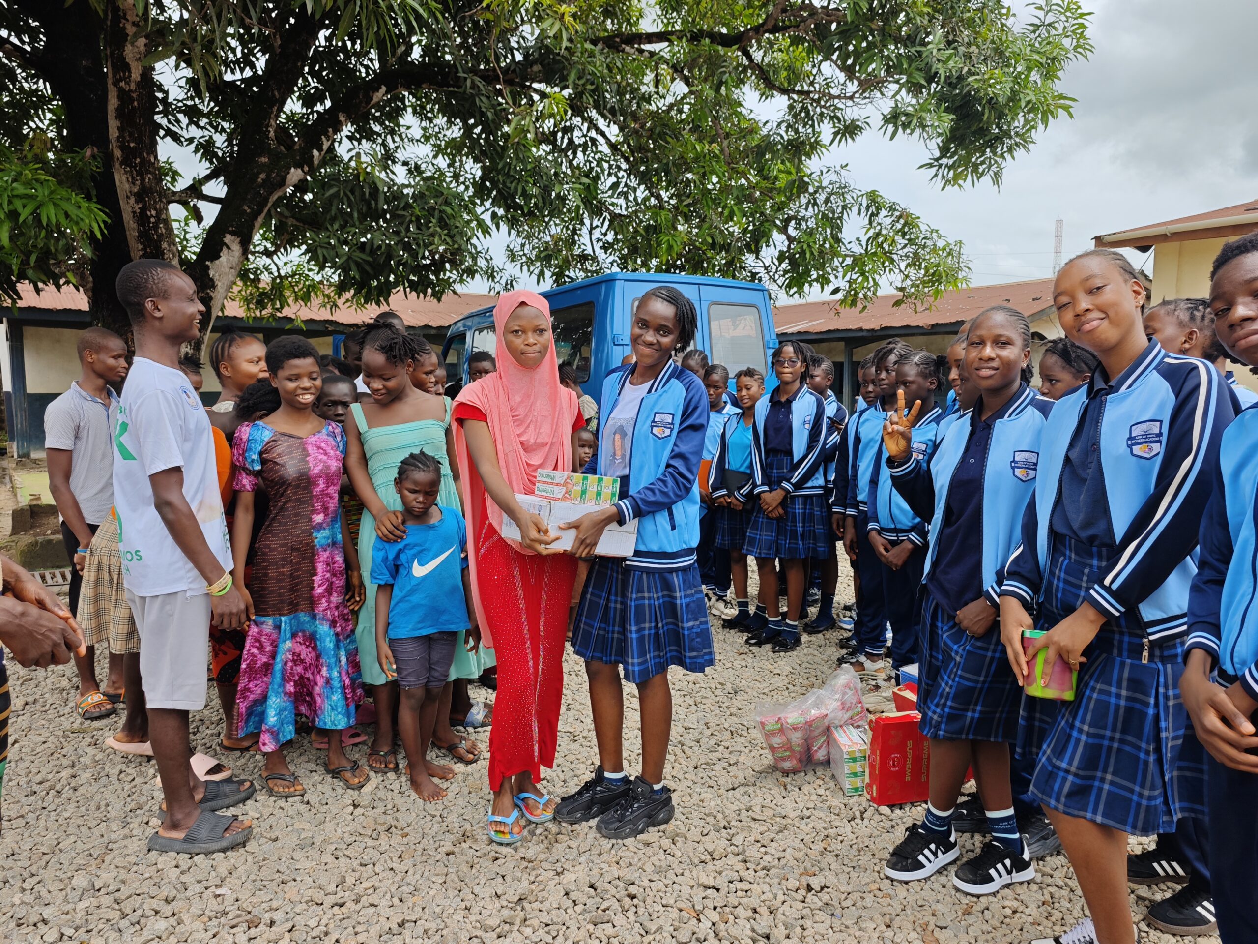 Ark of Hope students in blue uniforms taking part in community outreach beside a blue van